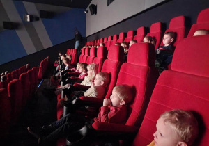 Dzieci siedzą w sali kinowej i oglądają bajkę