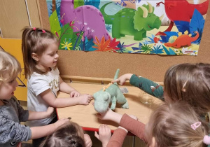 Dzieci oglądają maskotkę dinozaura