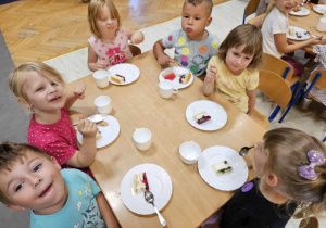 Dzieci jedzą kolorowe ciasto