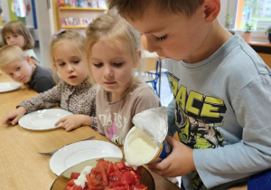 chłopiec wlewa jogurt do pomidorów