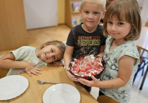 chłopiec i dwie dziewczynki prezentują gotową sałatkę z pomidorów