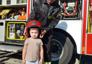 Chłopiec w kasku strażackim i panem strażakiem.