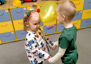 Dzieci tańczą w parze z balonem między czołami.