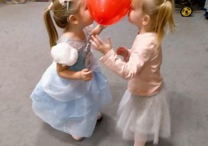 Dziewczynki tańczą z balonami miedzy czołami.