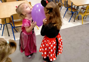 Dziewczynki tańczą z balonami miedzy czołami.
