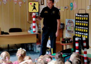 Strażnik Miejski pokazuje dzieciom znak "Uwaga dzieci".