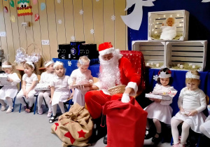 Św. Mikołaj wręcza dziewczynce prezent.