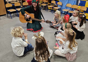 Pani Elf gra na gitarze a dzieci siedzą w kole