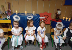 dziewczynki siedzące na krzesełkach w strojach aniołków