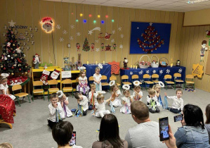 dzieci siedzące na dywanie podczas tańca świątecznego