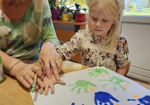 dzieci malują farbami i odbijają rękę na papierze