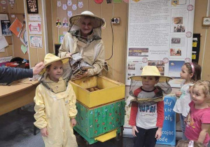 Nauczyciel i dwoje dzieci w stroju pszczelarskim