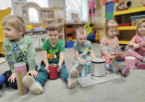 Dzieci siedzące na dywanie z własnoręcznie zrobionymi instrumentami