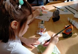 Dziewczynka z chłopcem malują gliniane wazoniki.
